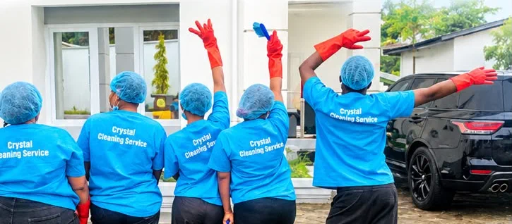 The Crystal Cleaning Service team in Buea, in blue uniforms and red gloves, waving
