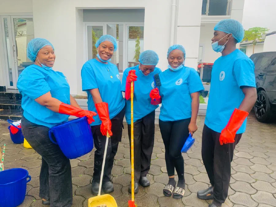 Five members of the Crystal Cleaning Service team smiling in blue uniforms with buckets, brooms and red gloves