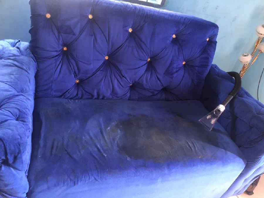 Extraction nozzle lifting a stain from a blue velvet sofa